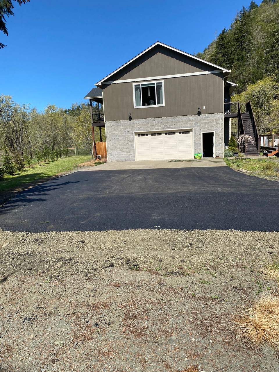 New asphalt apron in front of a two-car garage on a hillside home