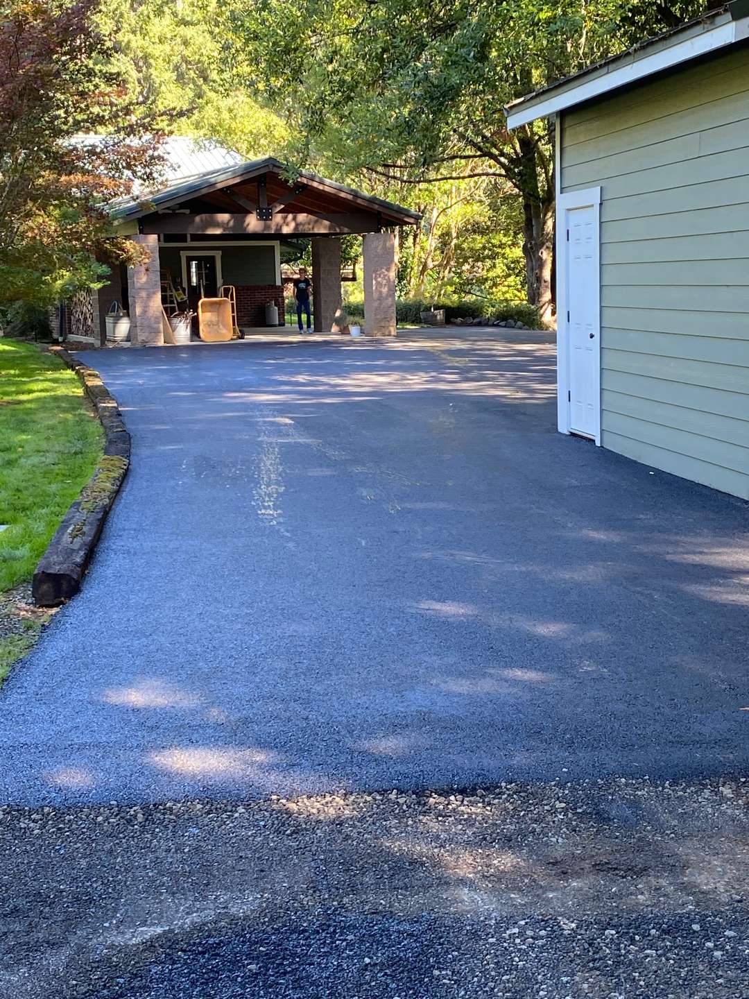 Fresh asphalt pad between a shop building and a covered workshop