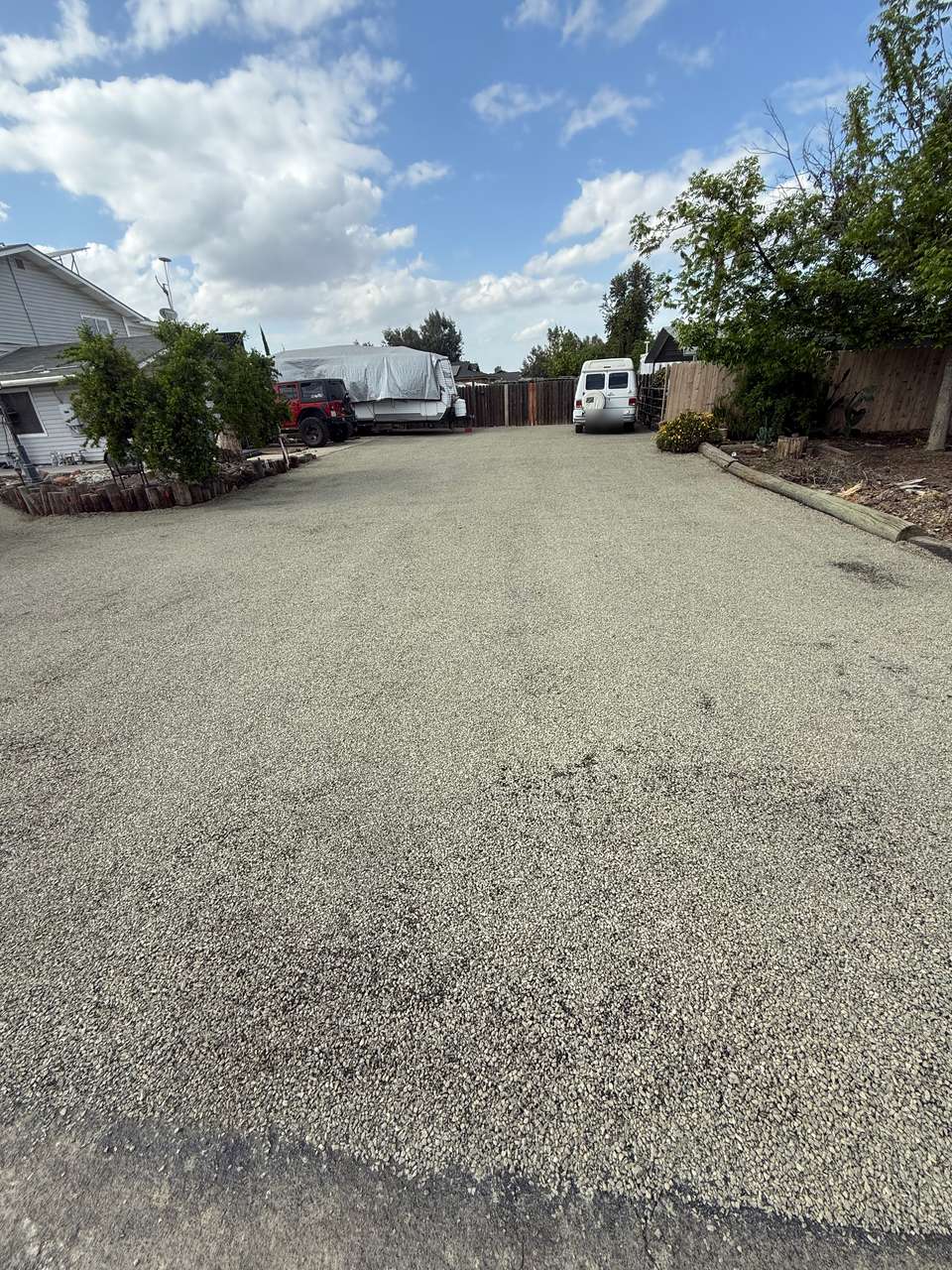 Wide chip seal parking area beside a home, with a fresh, even stone surface